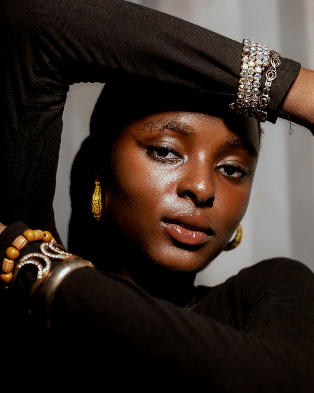 Elegant portrait of a woman adorned with bracelets and earrings, showcasing style.
