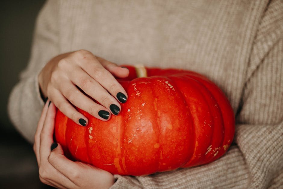 Close-up of a woman holding a bright orange pumpkin, symbolizing autumn.